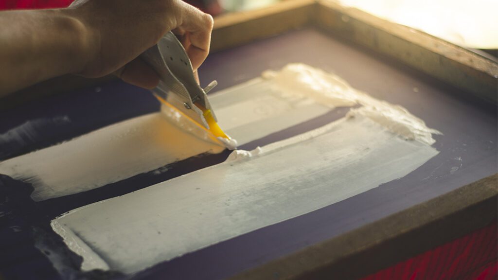 Applying ink on a screen for screen printing.