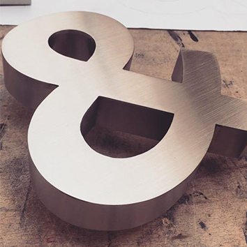 A large metallic ampersand symbol on a wooden surface.
